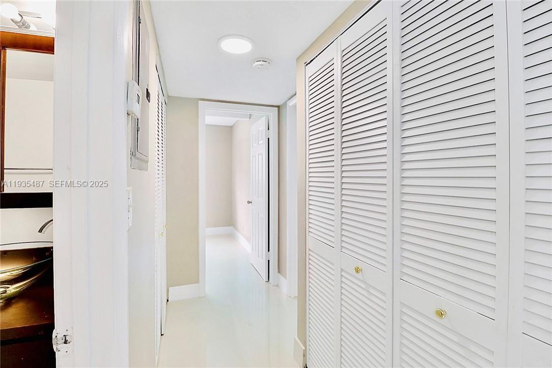 A hallway features white louvered closet doors, light tile flooring, and a recessed ceiling light — 1065 S Flagler Ave # 701, Pompano Beach FL 33060, POMPANO BEACH, FL