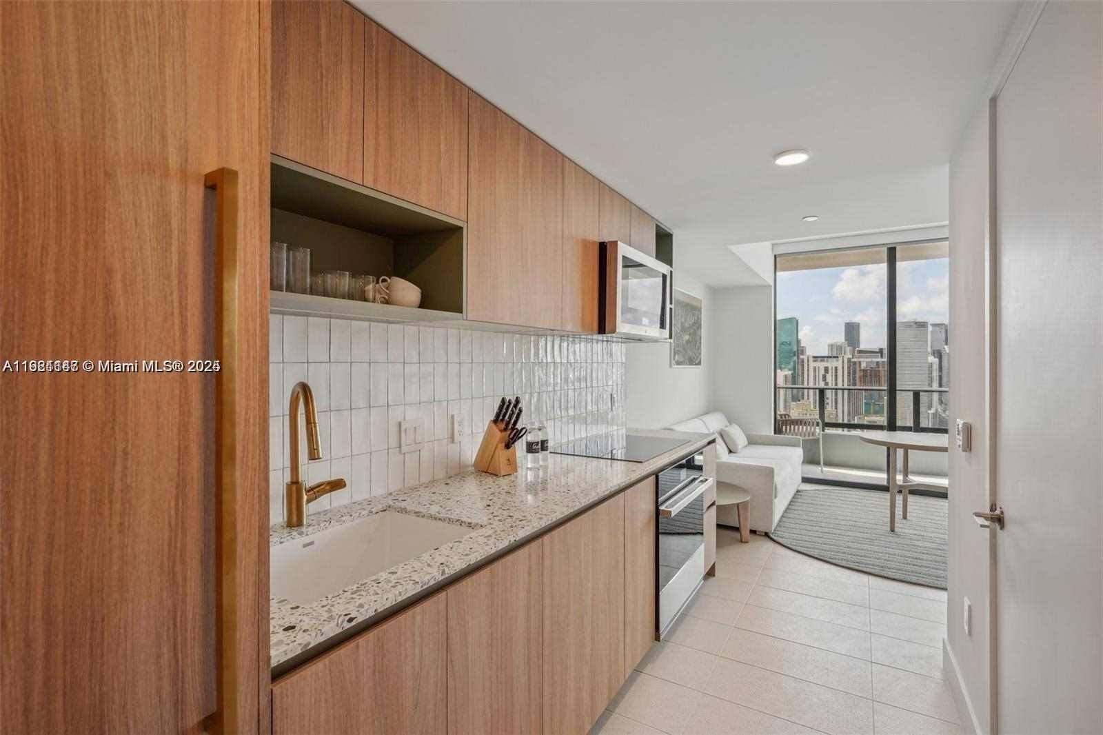 A modern kitchen with wood cabinets and a speckled countertop overlooks a city skyline — 159 NE 6th St # 4114, Miami FL 33132, MIAMI, FL