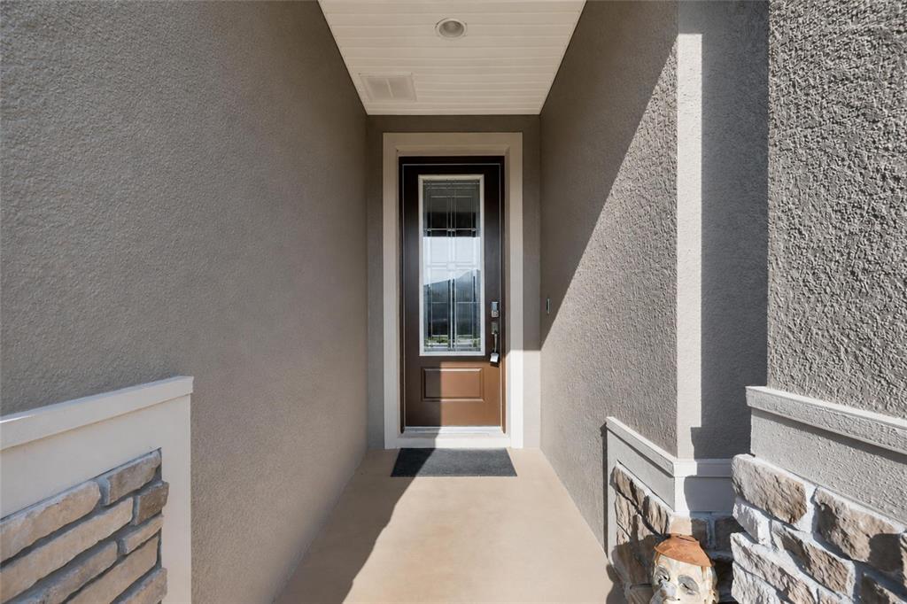 A covered entryway features a brown front door with a glass panel and stone accents — 4394 NW 54TH TERRACE, OCALA, FL