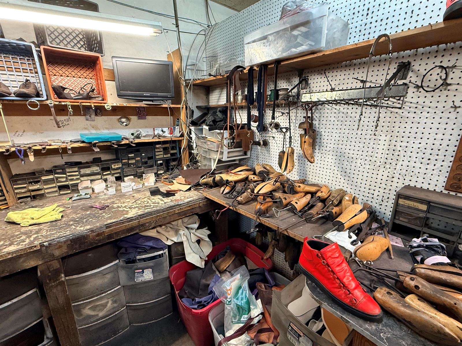 A cluttered shoe repair workshop features wooden workbenches, numerous shoe lasts, and various tools — 417 N State Road 7 # 417, Margate FL 33063, MARGATE, FL