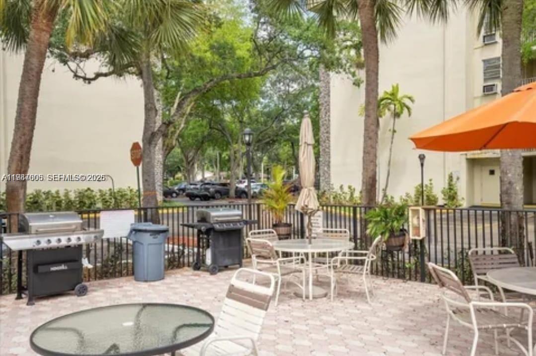 An outdoor patio area features grills, tables, chairs, and an orange umbrella near trees — 6700 Cypress Rd # 409, Plantation FL 33317, PLANTATION, FL