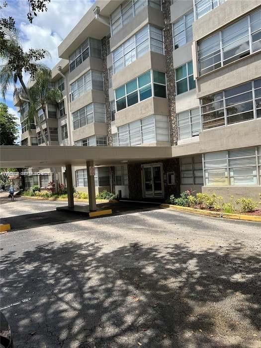 A multi-story apartment building features a covered entrance and a paved driveway — 6700 Cypress Rd # 409, Plantation FL 33317, PLANTATION, FL