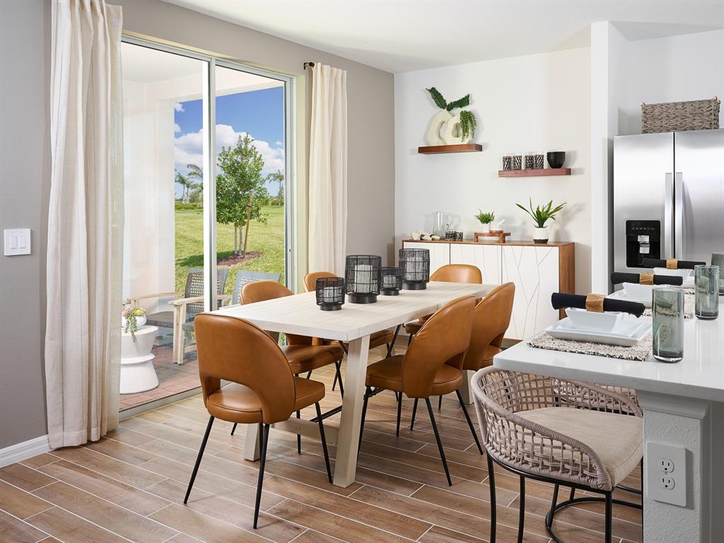 A dining area with a wooden table, leather chairs, and a sliding door to a patio — 706 IMPALA ROAD, LAKE ALFRED, FL