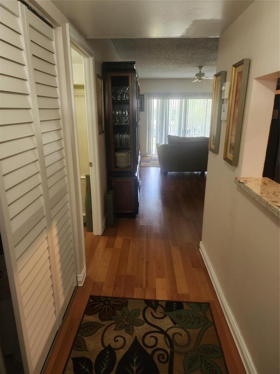 A hallway with wood flooring leads past a china cabinet toward a living room area — 7500 NW 4th Place, Margate FL 33063, MARGATE, FL