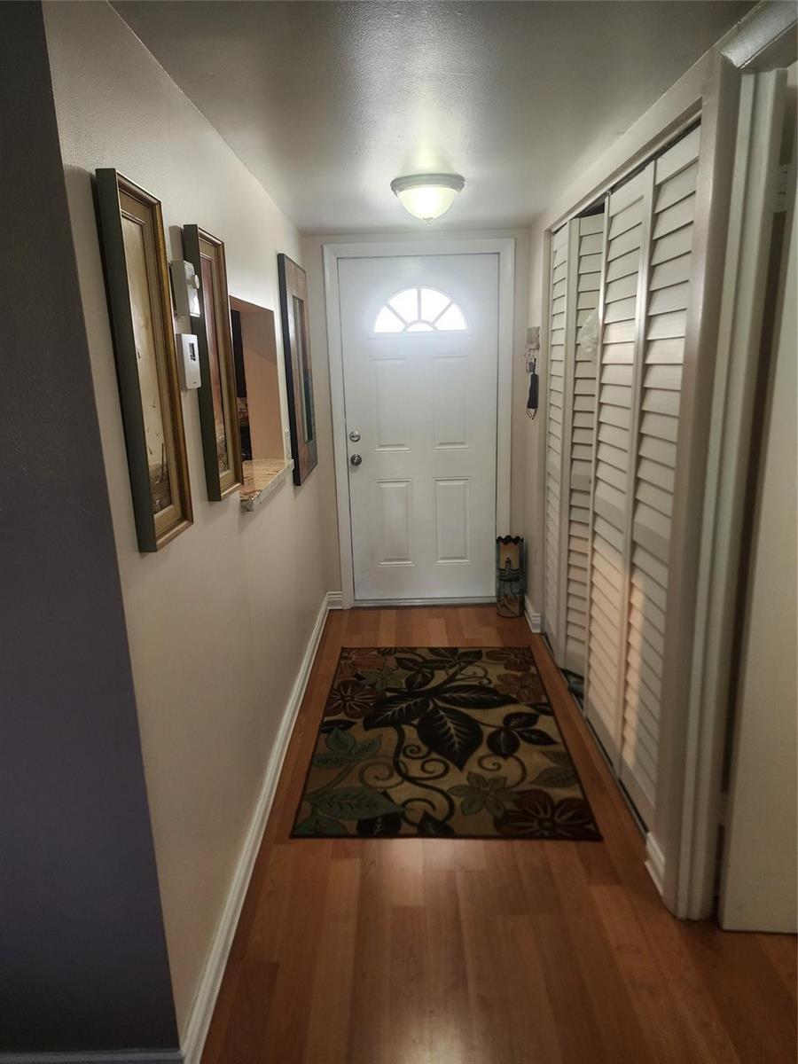 An entryway features wood flooring, a floral rug, a white door, and wall-mounted artwork — 7500 NW 4th Place, Margate FL 33063, MARGATE, FL
