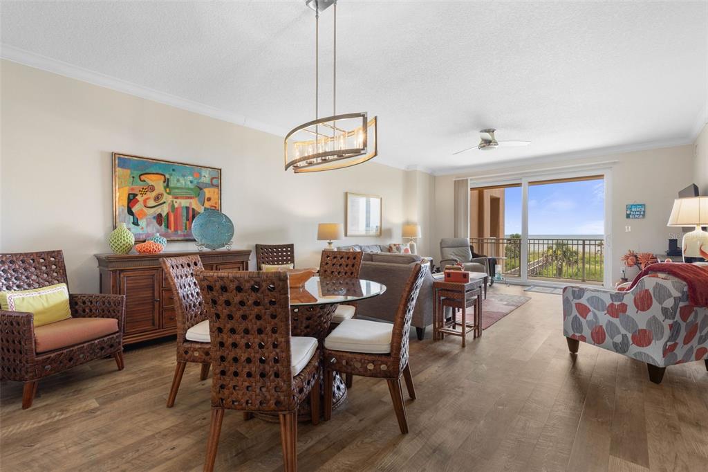 A dining area and living room with wicker furniture, wood flooring, and a balcony view — 60 SURFVIEW DRIVE UNIT 214, PALM COAST, FL