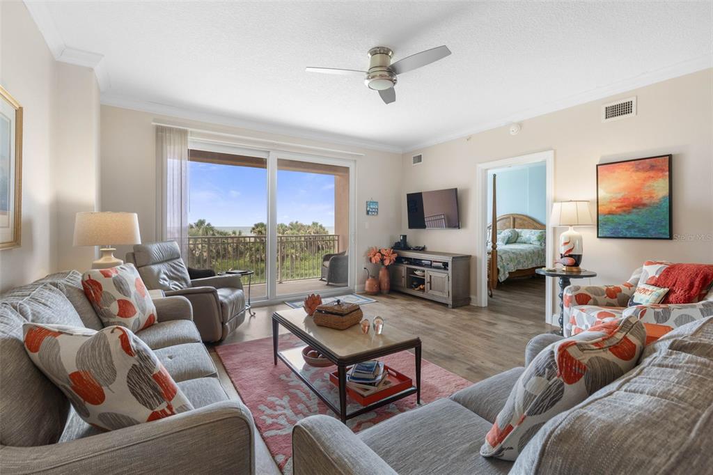 A living room with gray sofas, a coffee table, and a balcony overlooking the ocean — 60 SURFVIEW DRIVE UNIT 214, PALM COAST, FL