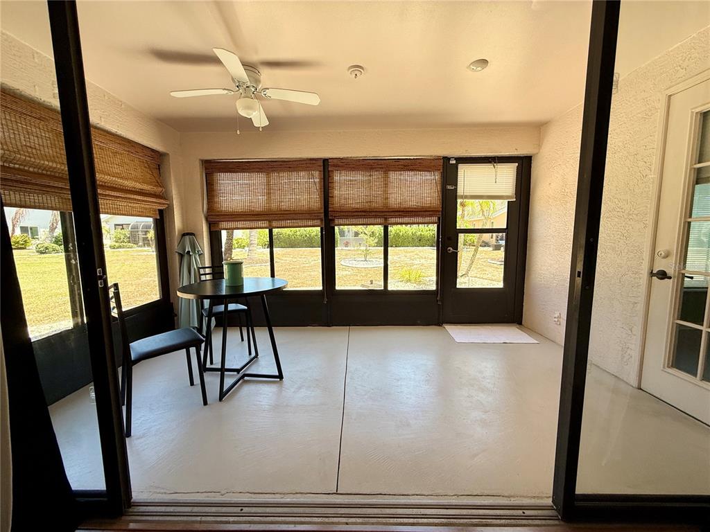 A screened-in porch with a ceiling fan, a small table, two chairs, and tile flooring — 1603 E DEL WEBB BOULEVARD, SUN CITY CENTER, FL