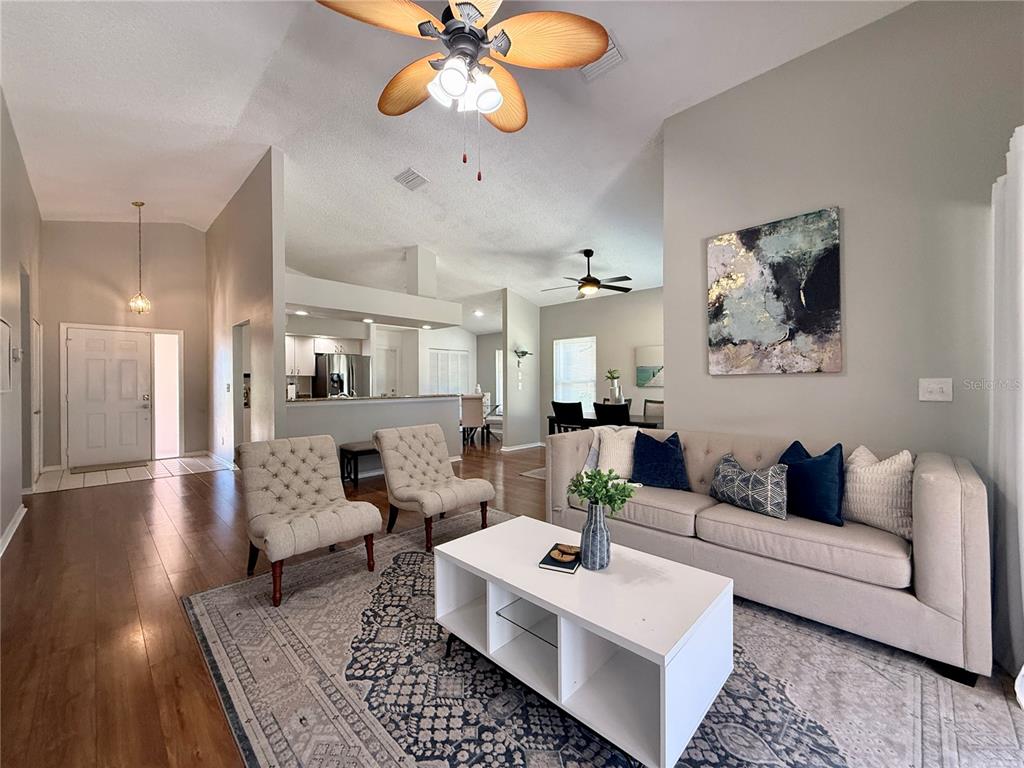 A living room features a beige sofa, two tufted chairs, and a white coffee table — 1603 E DEL WEBB BOULEVARD, SUN CITY CENTER, FL