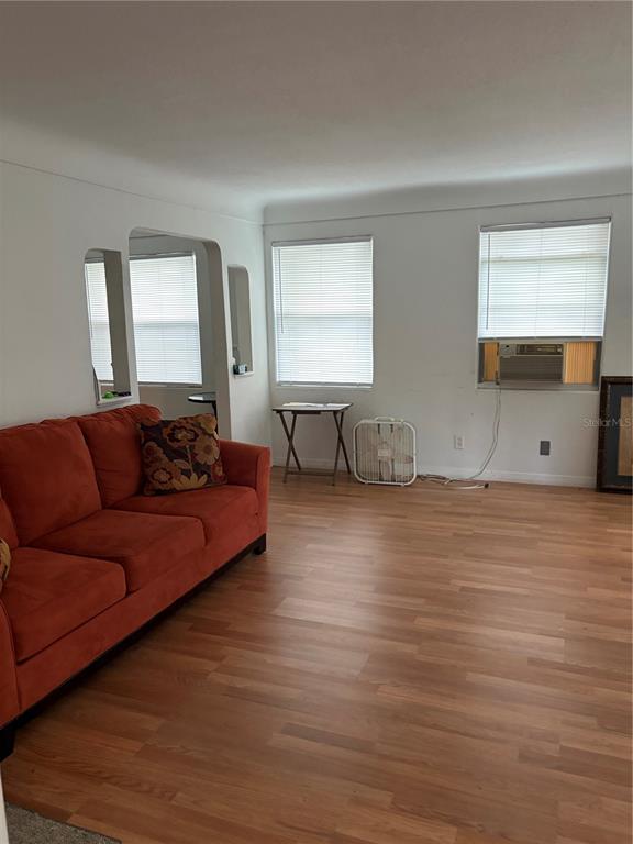 A living room features a burnt orange sofa, light wood flooring, and two windows — 915 WINCHESTER STREET, DAYTONA BEACH, FL