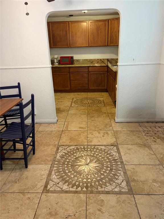 A kitchen with wood cabinets and stone tile flooring featuring decorative mosaic inlays — 915 WINCHESTER STREET, DAYTONA BEACH, FL