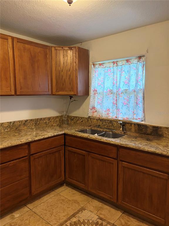 A kitchen with wood cabinets, granite countertops, a double sink, and tiled flooring — 915 WINCHESTER STREET, DAYTONA BEACH, FL