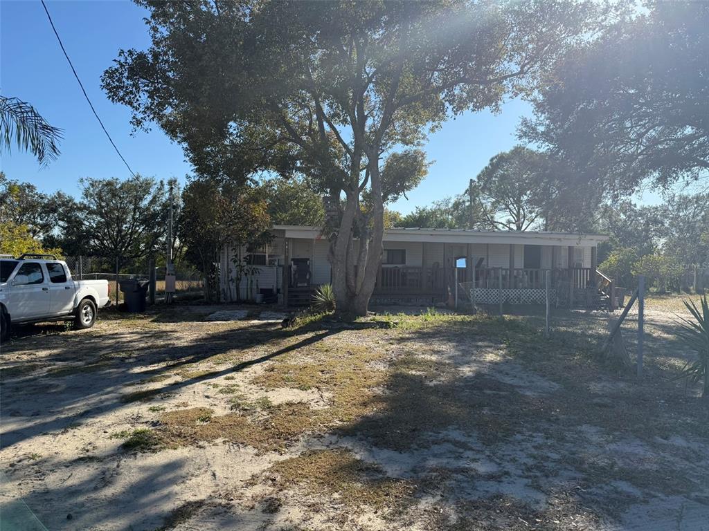 A single-story mobile home with a front porch sits on a sandy lot with trees — 9013 BURR DRIVE, POLK CITY, FL