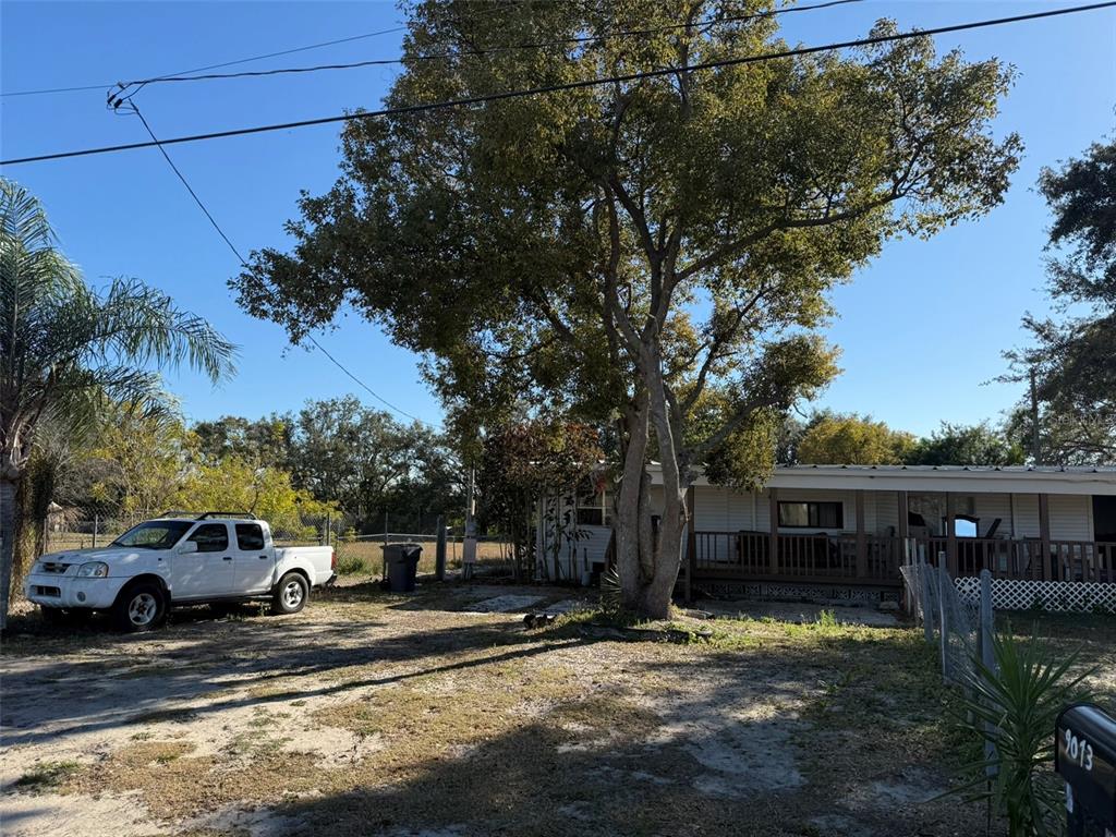 A white pickup truck is parked on a dirt lot next to a mobile home — 9013 BURR DRIVE, POLK CITY, FL