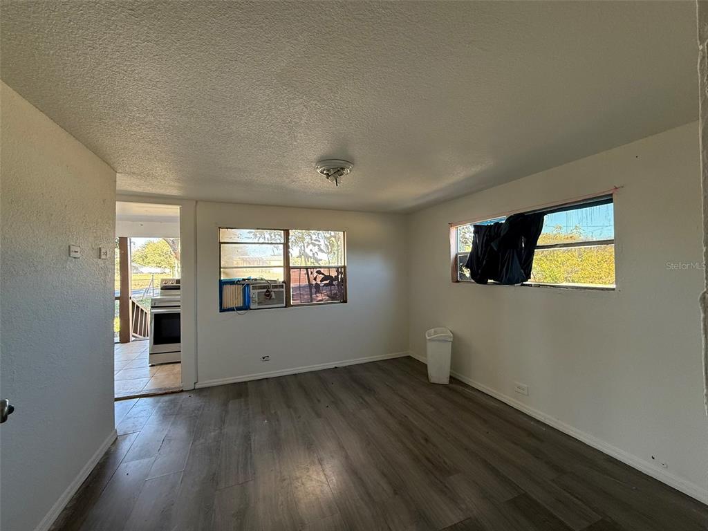 A room with wood-look flooring, white walls, and two windows looking out toward a kitchen — 9013 BURR DRIVE, POLK CITY, FL