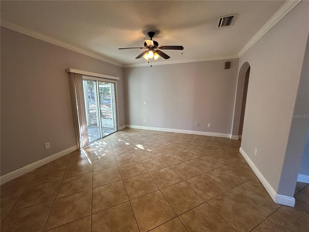 An empty room features light-colored walls, tile flooring, a ceiling fan, and sliding glass doors — 3721 S LAKE ORLANDO PARKWAY UNIT 7, ORLANDO, FL