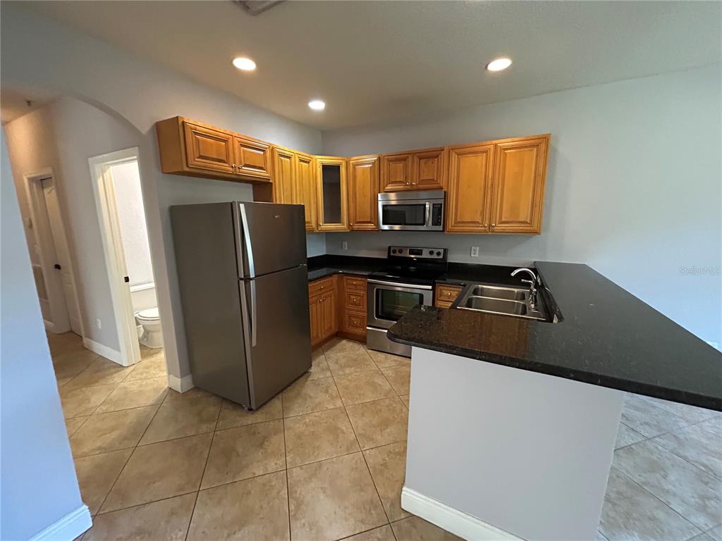 A kitchen features light wood cabinets, stainless steel appliances, and a dark granite countertop — 3721 S LAKE ORLANDO PARKWAY UNIT 7, ORLANDO, FL