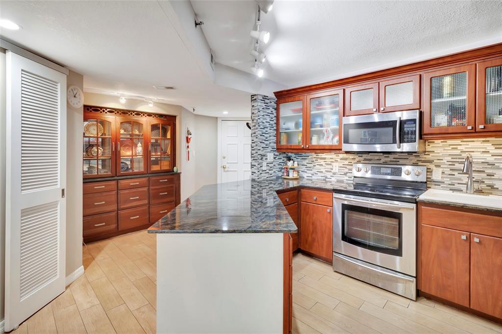 A kitchen features cherry wood cabinets, granite countertops, stainless steel appliances, and tile flooring — 400 E COLONIAL DRIVE UNIT 1609, ORLANDO, FL