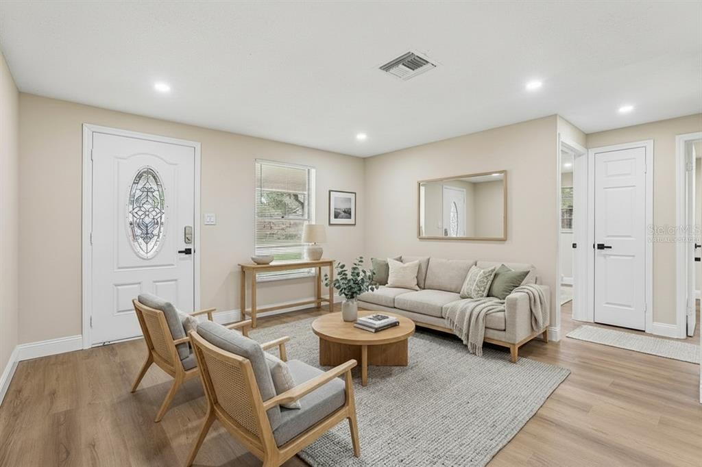 A living room with light wood floors, a beige sofa, two armchairs, and a coffee table — 518 LAVON DRIVE, ALTAMONTE SPRINGS, FL
