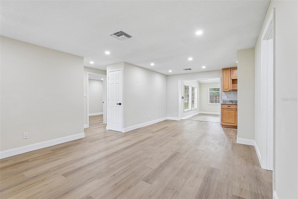A bright living area with light wood-look flooring, recessed lighting, and an adjacent kitchen space — 518 LAVON DRIVE, ALTAMONTE SPRINGS, FL