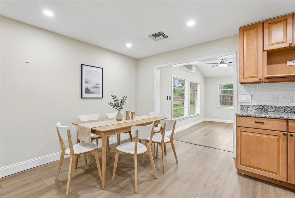 A dining area with a wooden table and white chairs sits beside a kitchen — 518 LAVON DRIVE, ALTAMONTE SPRINGS, FL