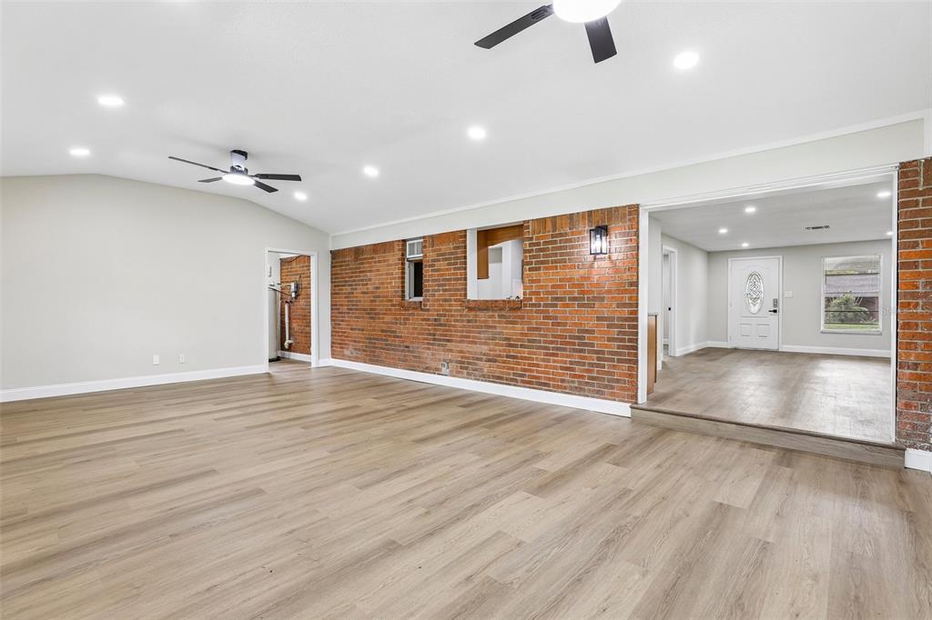 A spacious room features light wood-look flooring, a brick accent wall, and recessed ceiling lighting — 518 LAVON DRIVE, ALTAMONTE SPRINGS, FL