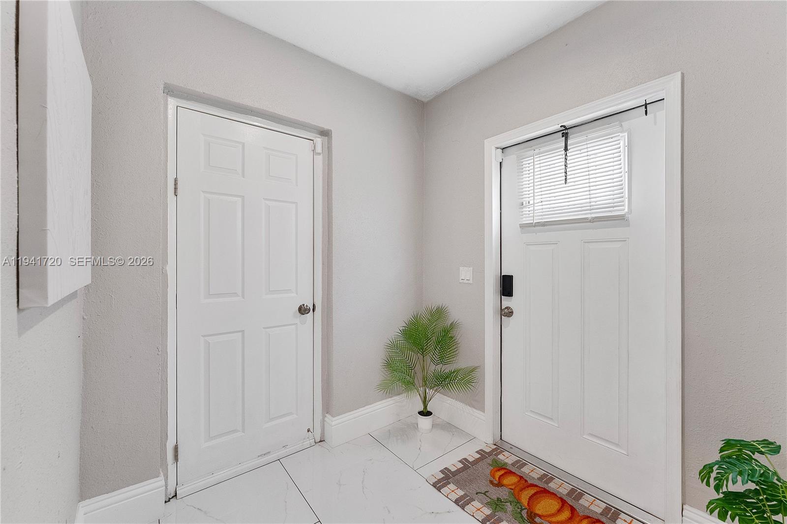 An entryway features white tile floors, two white doors, and a small potted plant — 2227 Cody St, Hollywood FL 33020, HOLLYWOOD, FL