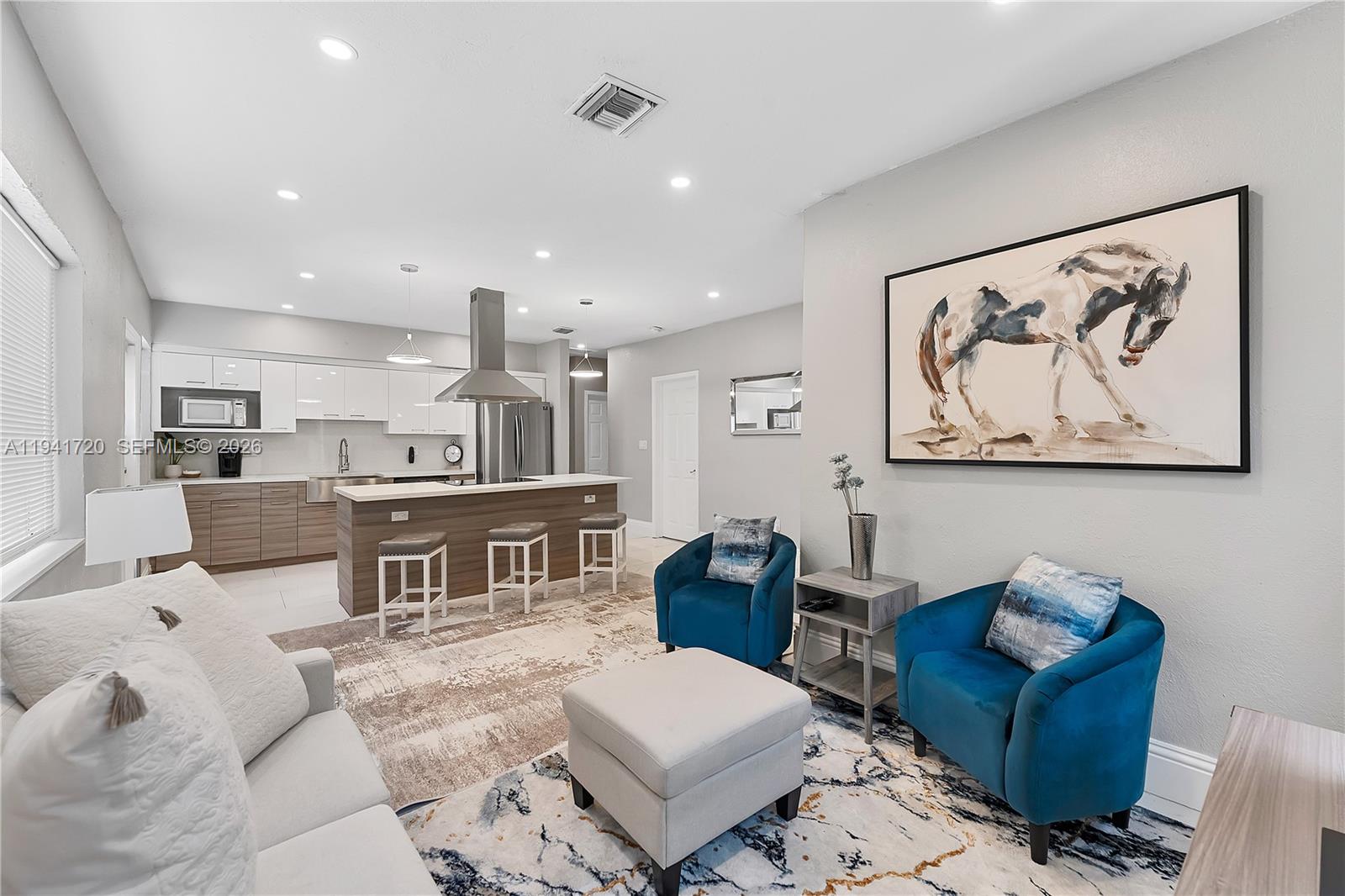 A living room with blue armchairs and a kitchen with a breakfast bar and stools — 2227 Cody St, Hollywood FL 33020, HOLLYWOOD, FL