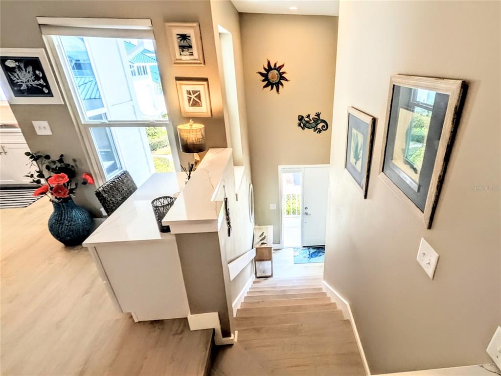 A staircase leads down to an entryway with a white door and wall decor — 958 SANDPIPER CIRCLE UNIT 958, BRADENTON, FL