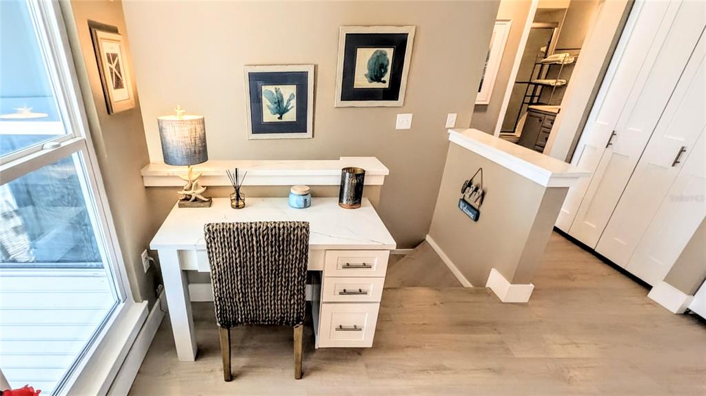 A white desk with a woven chair sits in a room with light wood flooring — 958 SANDPIPER CIRCLE UNIT 958, BRADENTON, FL