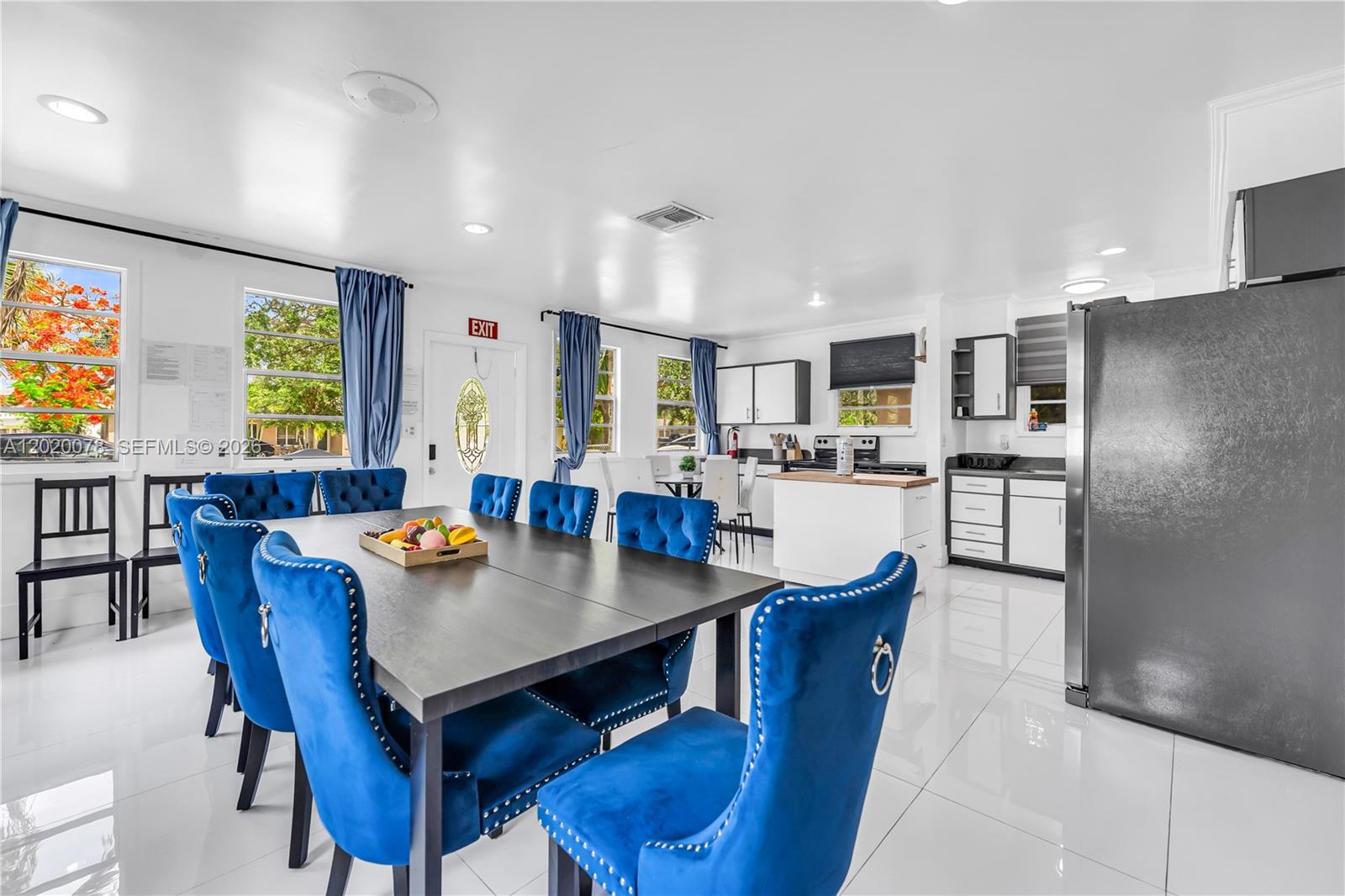 A dining area with blue velvet chairs and a kitchen with white cabinets and appliances — 1738 N 16th Ct, Hollywood FL 33020, HOLLYWOOD, FL