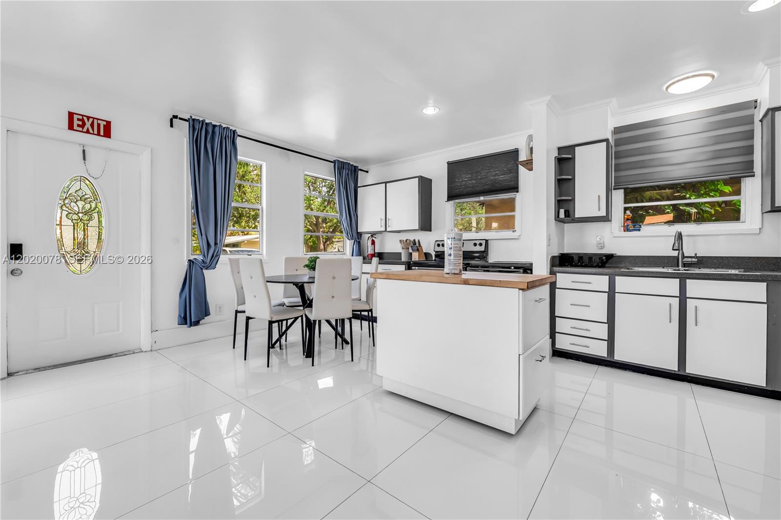 A kitchen and dining area features white cabinets, a central island, and glossy tile floors — 1738 N 16th Ct, Hollywood FL 33020, HOLLYWOOD, FL