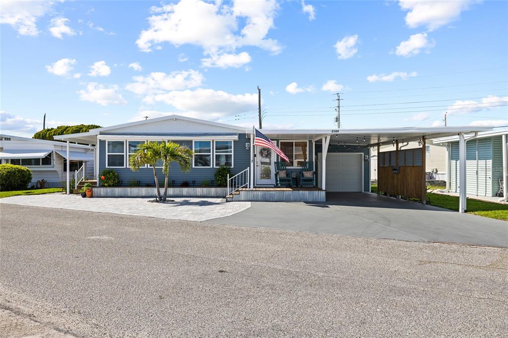 A blue manufactured home features a paved driveway, a carport, and a front porch — 2109 OHIO AVENUE, BRADENTON, FL