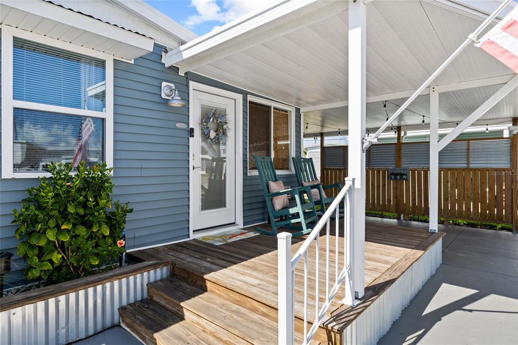 A blue-sided home features a wooden porch with two rocking chairs and a metal roof — 2109 OHIO AVENUE, BRADENTON, FL