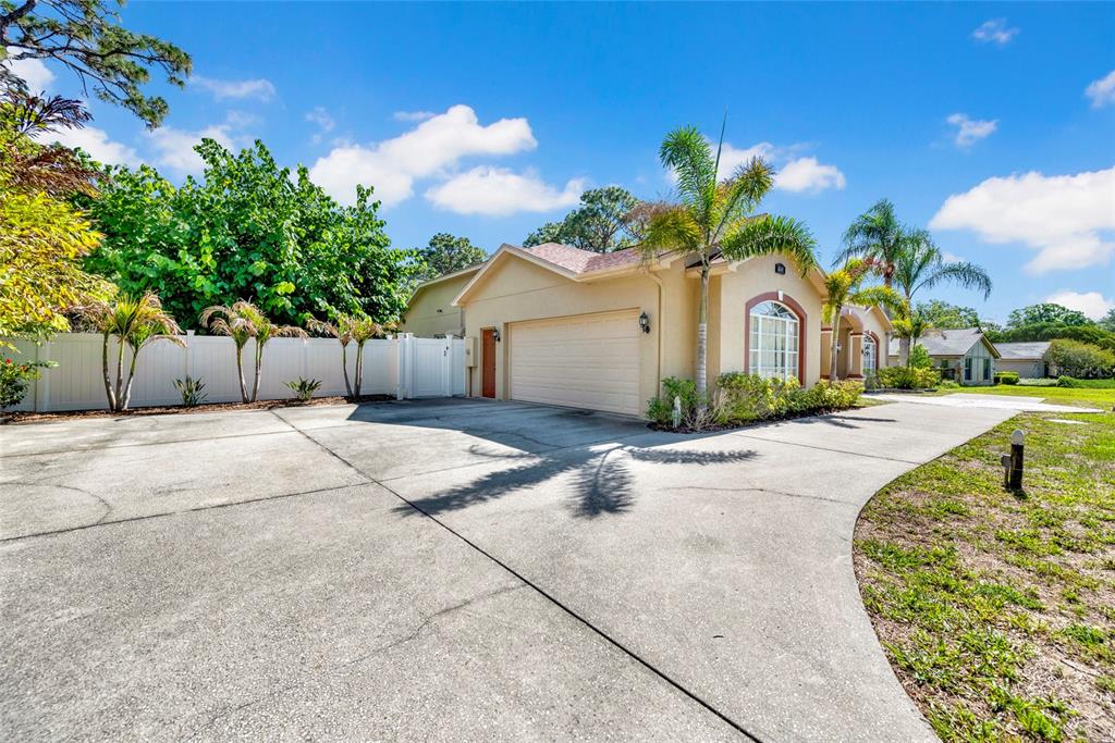 A beige house with a two-car garage and a large concrete driveway — 6341 GOVERNORS DRIVE, NEW PORT RICHEY, FL
