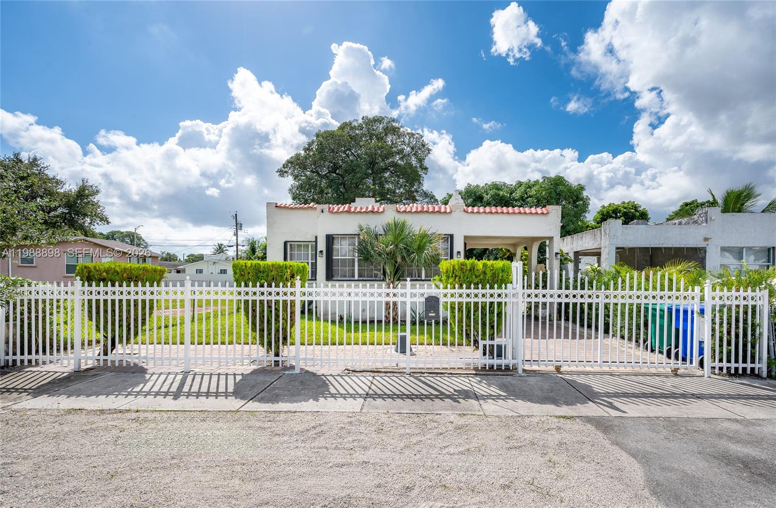 A white house with a red tile roof sits behind a white metal fence — 1844 NW 47th St, Miami FL 33142, MIAMI, FL