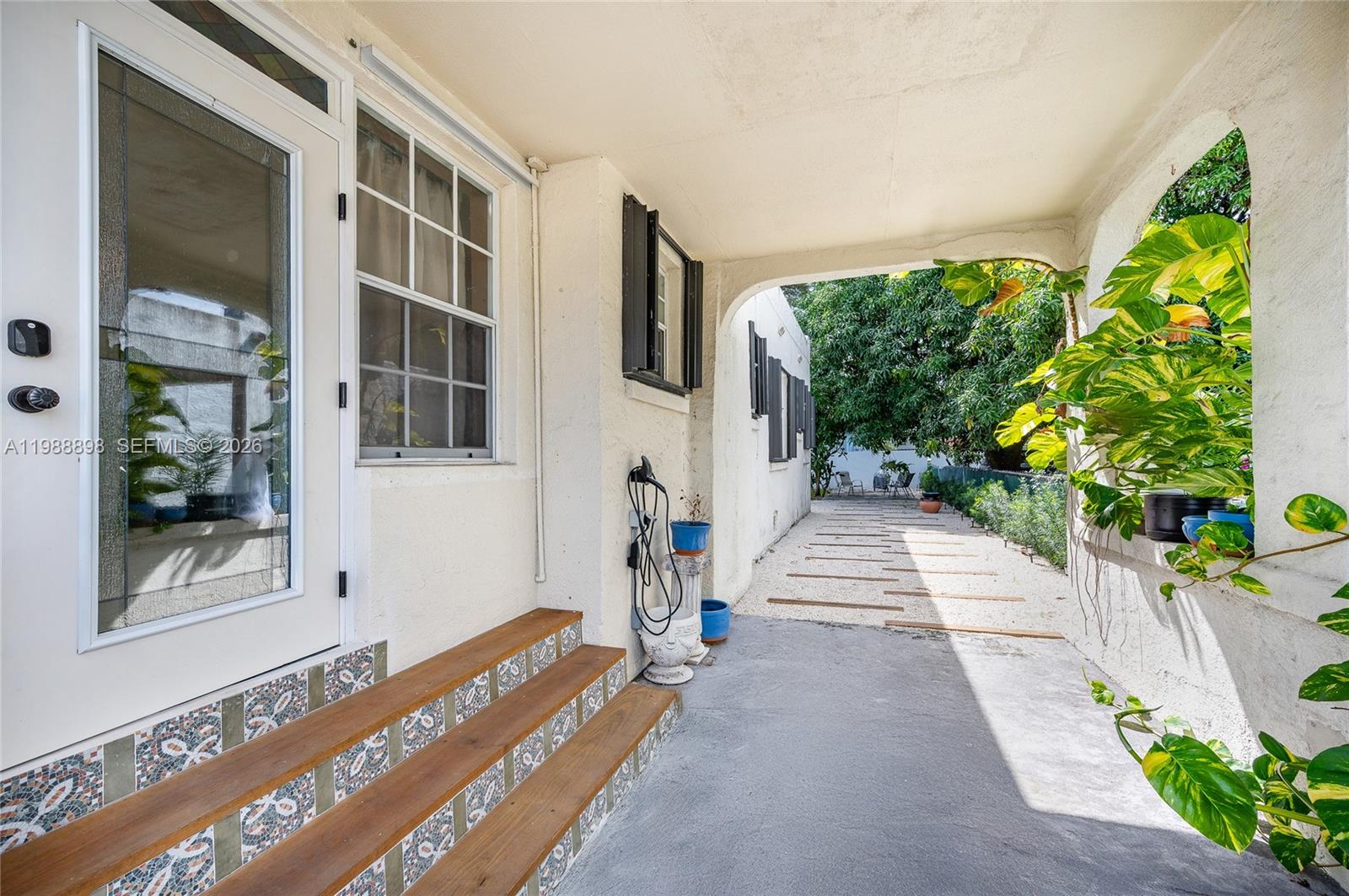 A covered porch features tiled steps leading to a white door and a gravel walkway — 1844 NW 47th St, Miami FL 33142, MIAMI, FL