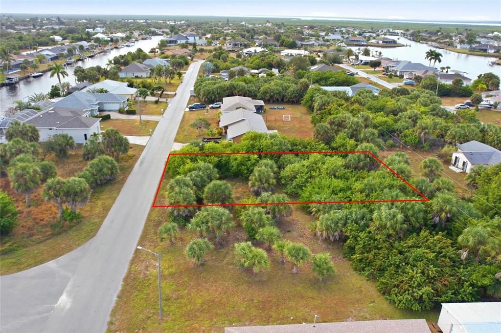 An aerial view shows a vacant, wooded residential lot outlined in red along a street — 4081 ROSE ARBOR CIRCLE, PORT CHARLOTTE, FL
