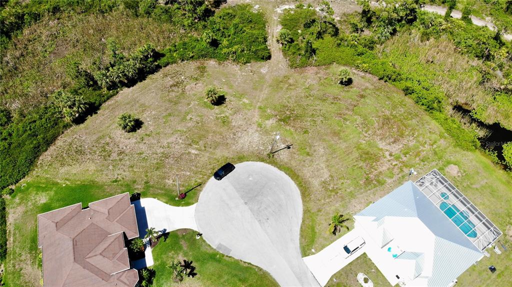 An aerial view shows a vacant, curved residential lot situated between two existing houses — 89 PINE VALLEY PLACE, ROTONDA WEST, FL