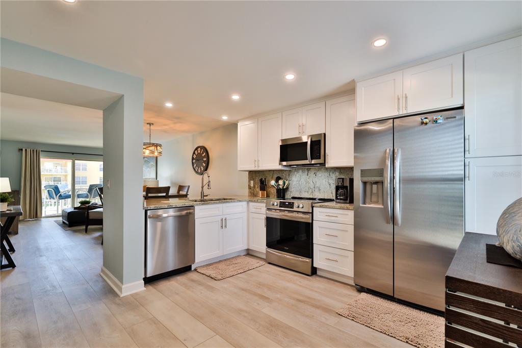 A kitchen with white cabinets, stainless steel appliances, and light wood flooring — 3801 S ATLANTIC AVENUE UNIT UT204, NEW SMYRNA BEACH, FL