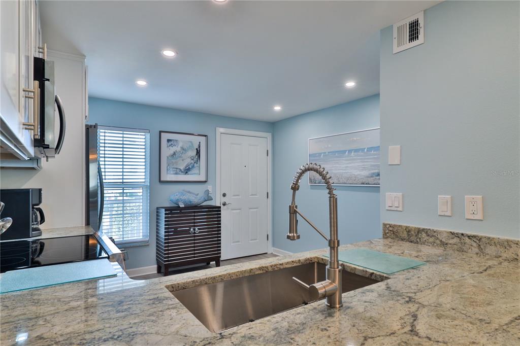 A kitchen features granite countertops, a stainless steel sink, and light blue walls — 3801 S ATLANTIC AVENUE UNIT UT204, NEW SMYRNA BEACH, FL