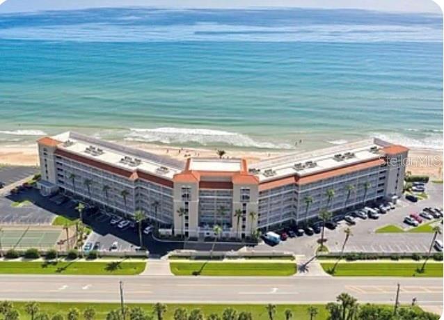 An aerial view shows a large, multi-story beachfront hotel with a parking lot and tennis courts — 5501 ATLANTIC UNIT 107, NEW SMYRNA BEACH, FL