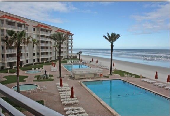 An elevated view of a beachfront resort with multiple swimming pools and lounge chairs — 5501 ATLANTIC UNIT 107, NEW SMYRNA BEACH, FL
