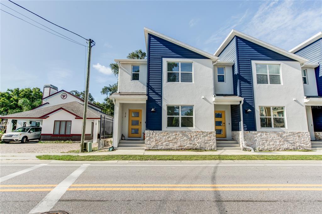 A two-story townhouse with blue siding, white stucco, and stone veneer sits beside a road — 214 E CHURCH AVENUE, LONGWOOD, FL