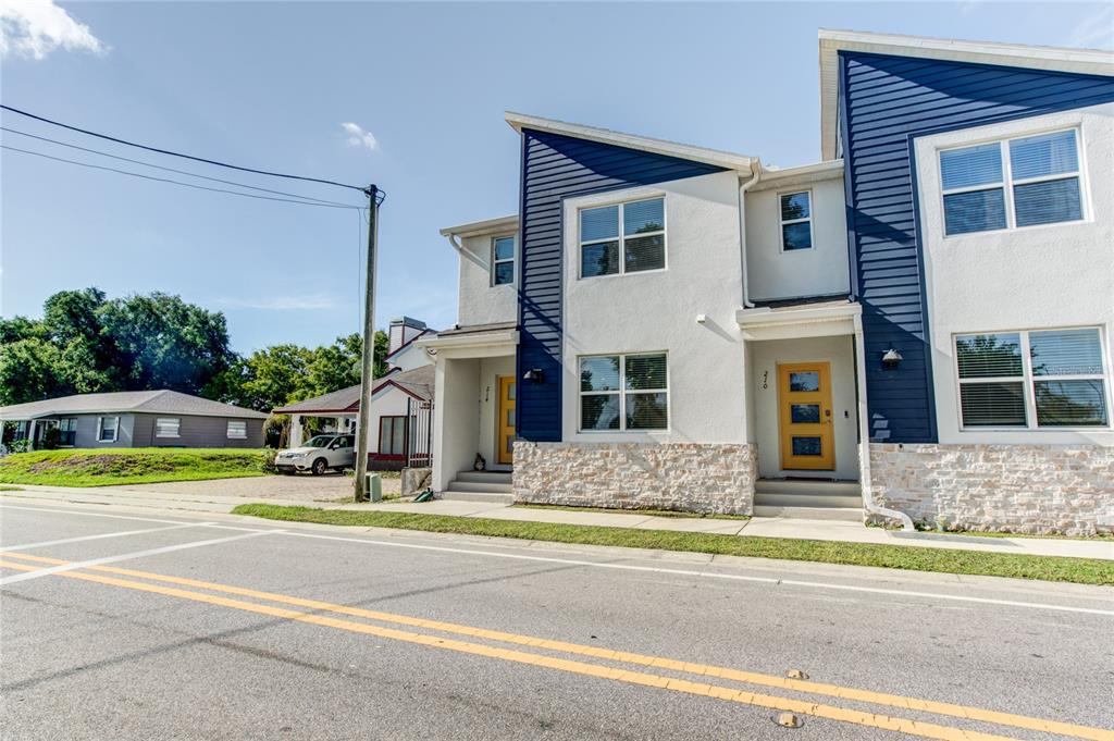 A street-level view of two modern townhomes with blue siding, white stucco, and stone accents — 214 E CHURCH AVENUE, LONGWOOD, FL