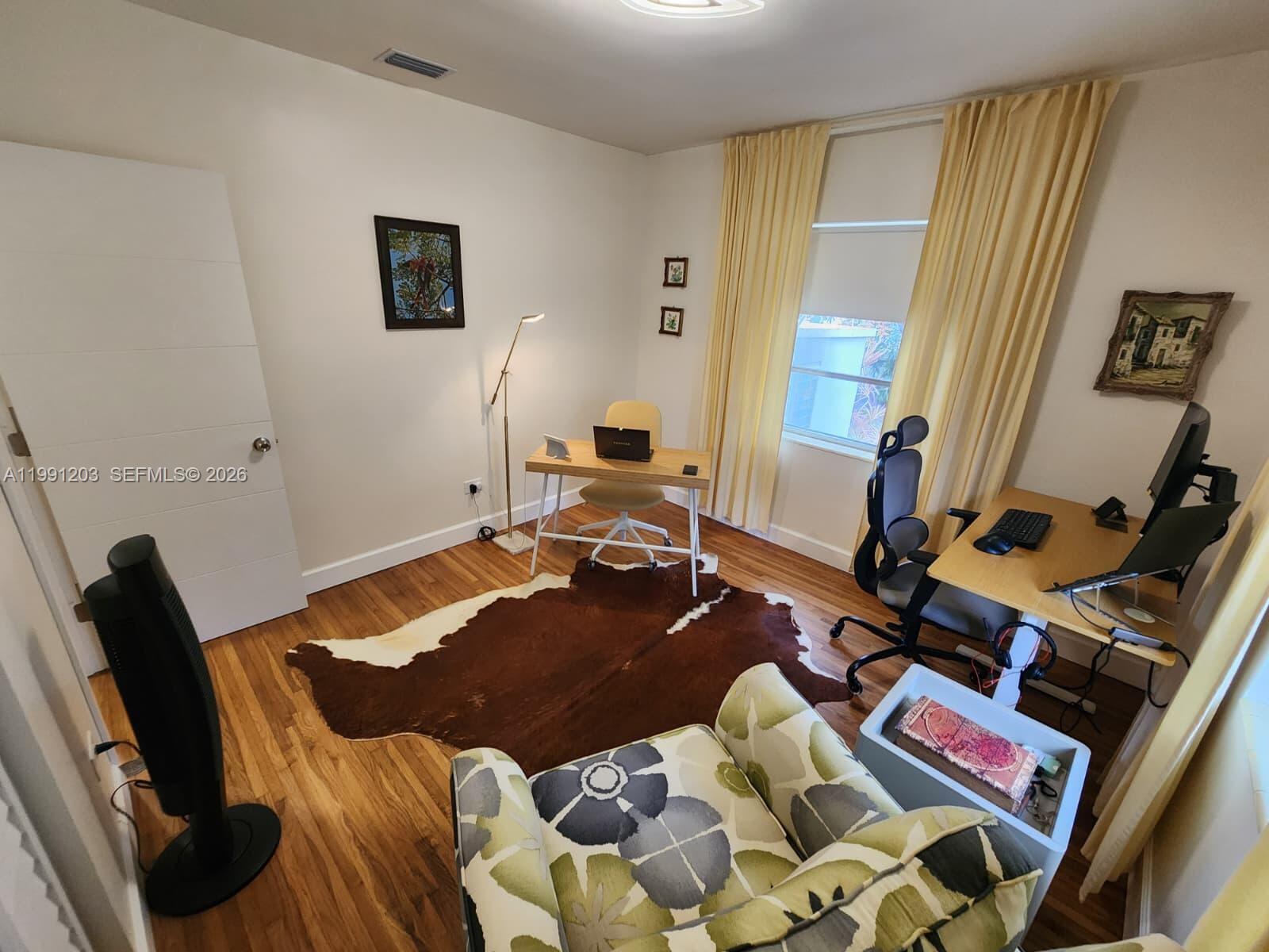 A home office features hardwood floors, a cowhide rug, two desks, and a patterned armchair — 831 Plover Ave, Miami Springs FL 33166, MIAMI SPRINGS, FL