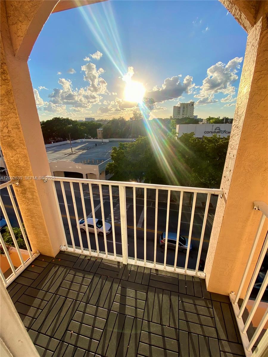 A balcony with dark tiled flooring overlooks a street, parking lot, and distant buildings — 199 SW 12th Ave # C, Miami FL 33130, MIAMI, FL