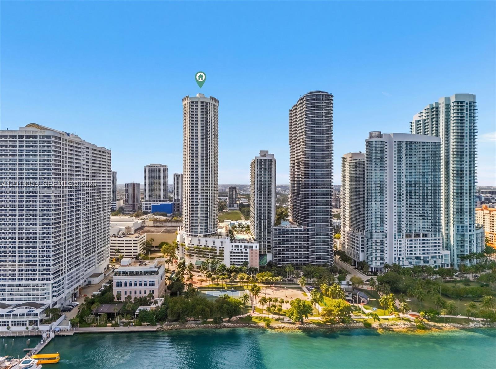 An aerial view shows a circular high-rise residential tower surrounded by other skyscrapers and greenery — 1750 N Bayshore Dr # 1407, Miami FL 33132, MIAMI, FL