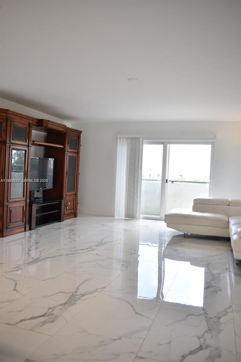 A living room features white marble floors, a large wooden entertainment center, and a white sofa — 8024 Tatum Waterway Dr # 5A, Miami Beach FL 33141, MIAMI BEACH, FL