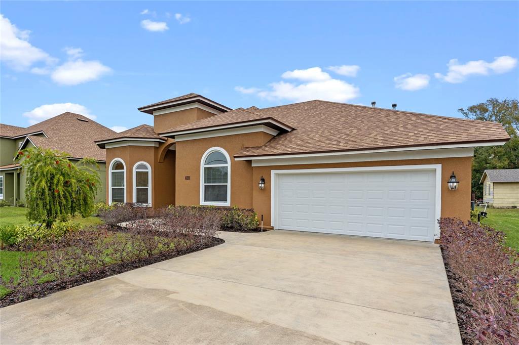 A tan stucco house features a two-car garage, arched windows, and a brown shingled roof — 1943 SIPES AVENUE, SANFORD, FL